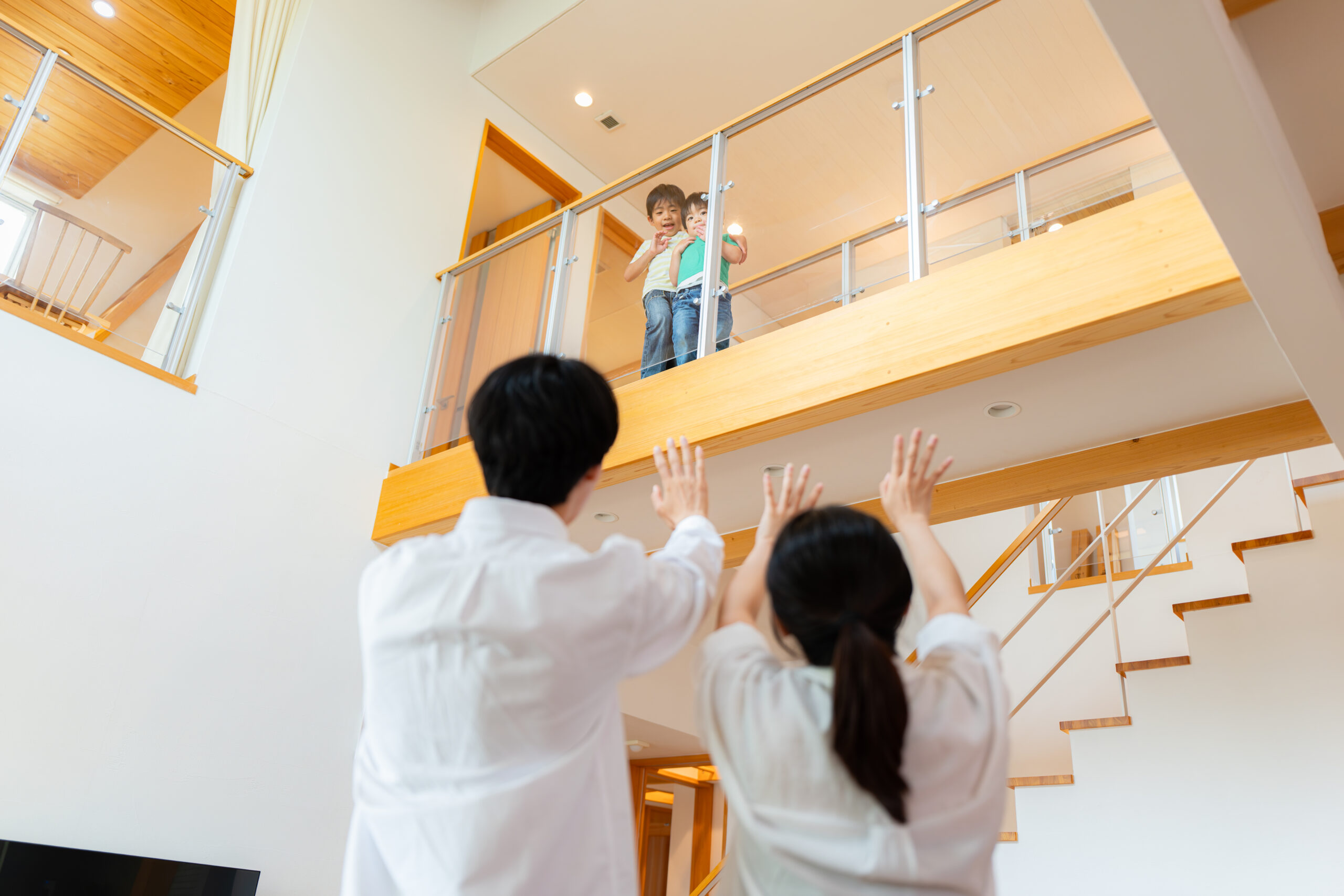 吹き抜けごしに手を振り合うご家族（デモ）